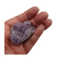 A hand holding a piece of amethyst with purple points on a base of grey stone