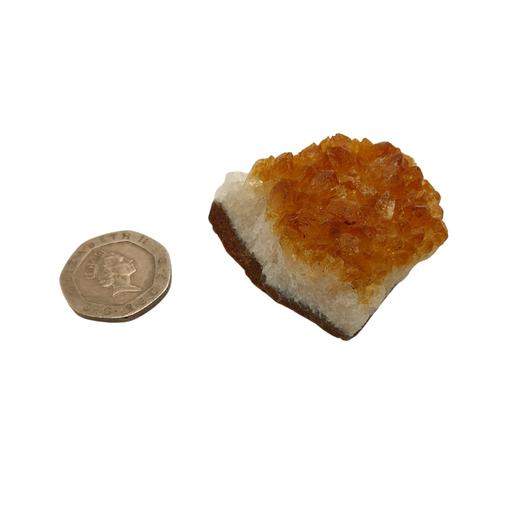 A cluster of citrine with yellow crystal points on a white base next to a 20 pence 