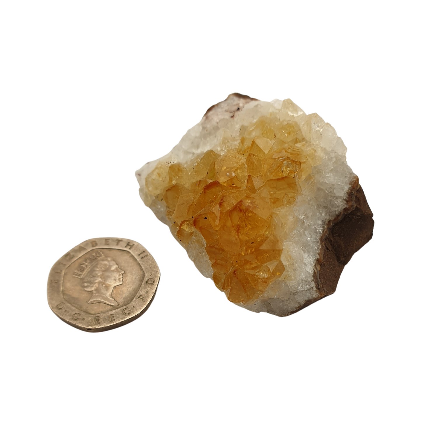 A cluster of citrine with yellow crystal points on a white base next to a 20 pence 