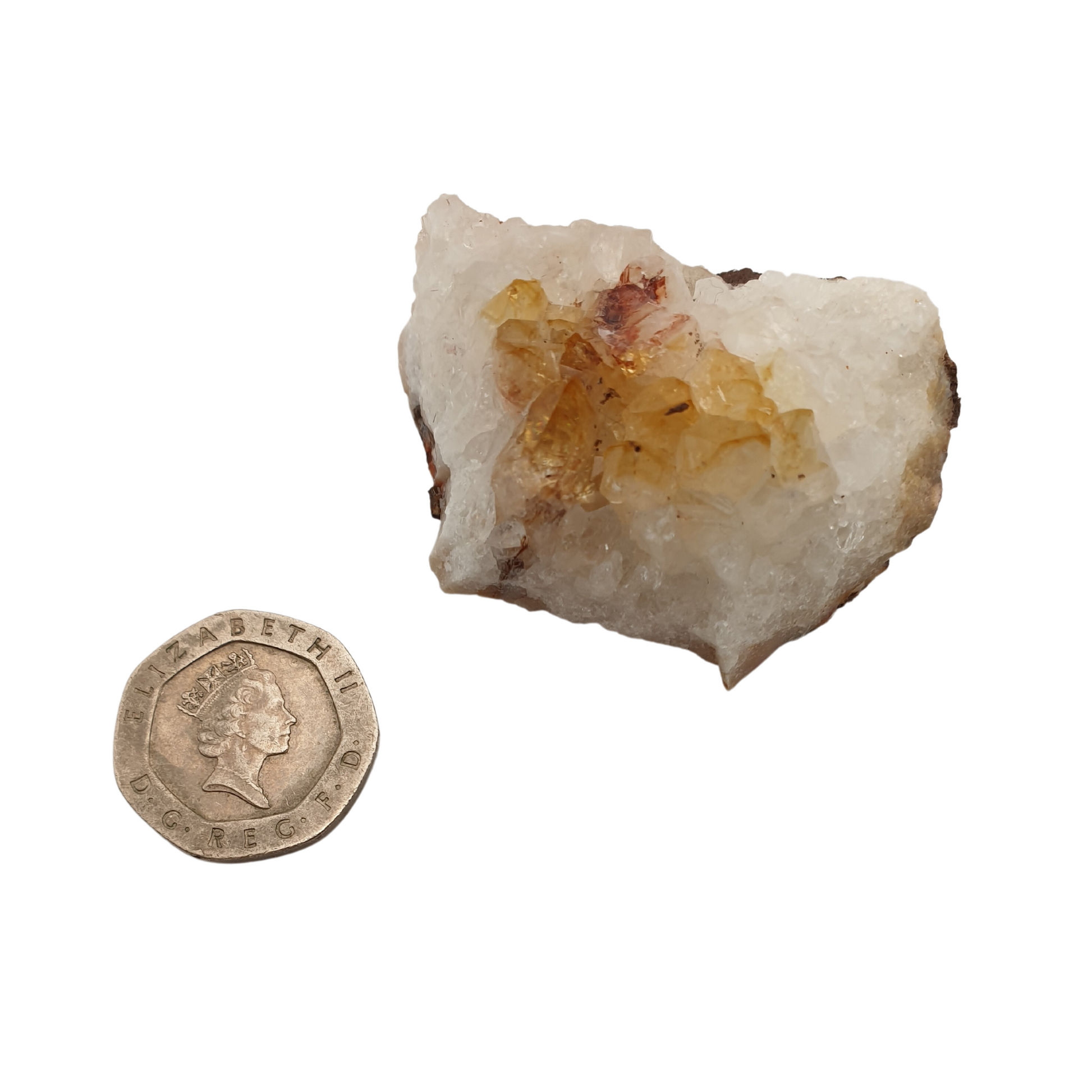 A cluster of citrine with yellow crystal points on a white base next to a 20 pence 