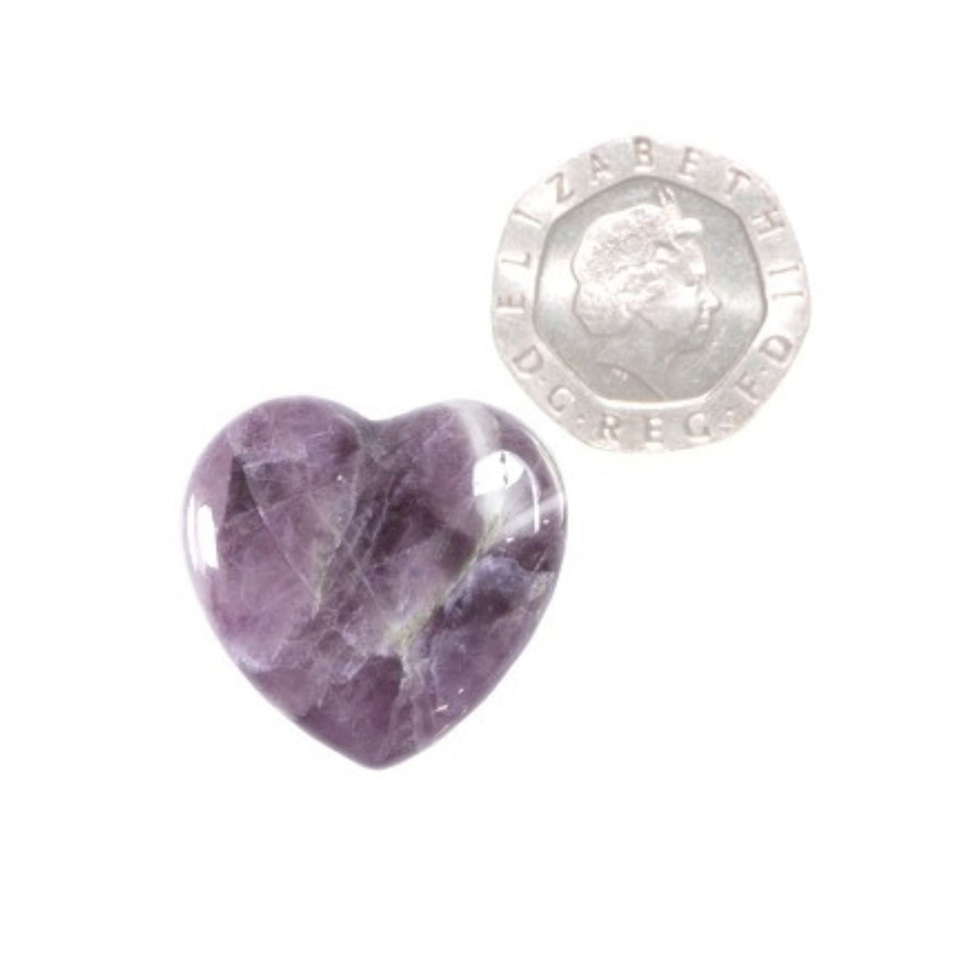 an amethyst crystal carved into a heart shape next to a 20 pence piece on a white background