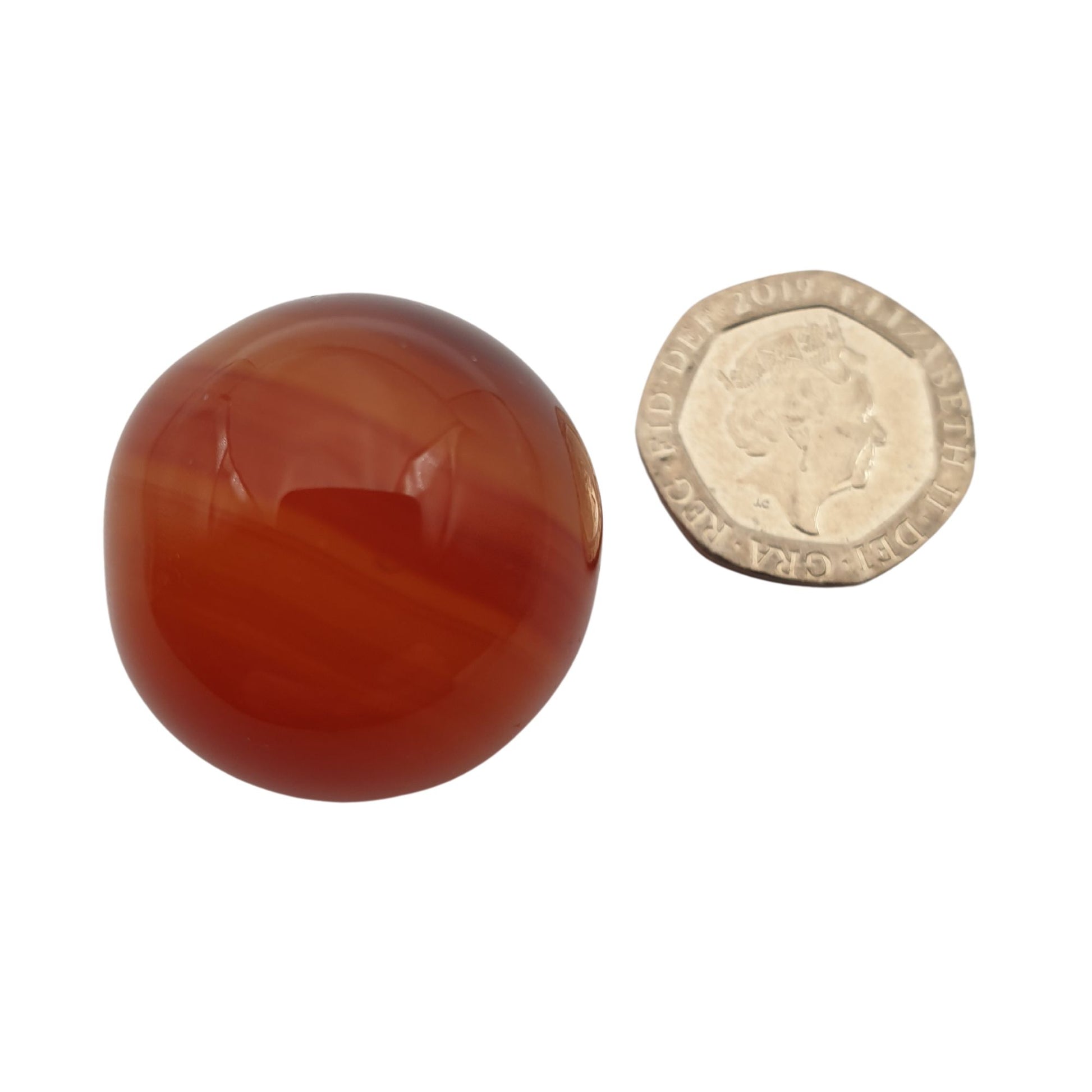 Small round Carnelian Crystal next to a twenty pence piece 