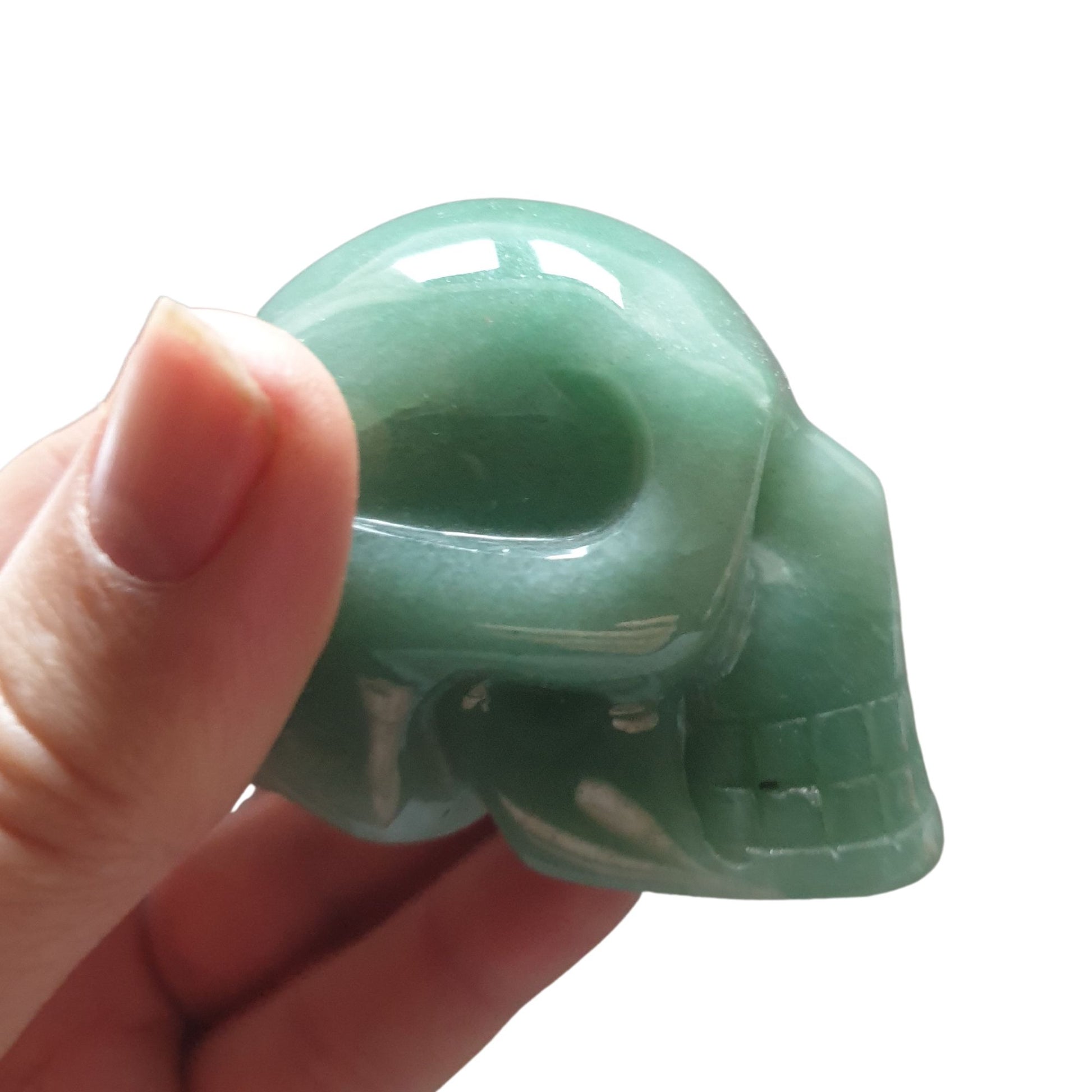 A hand showing a side ways view of a skull carved from Green Aventurine Crystal